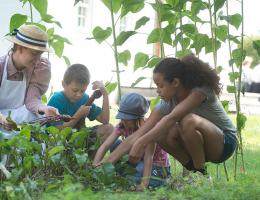 An adult in historic costume and kids gardening