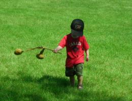 A young boy catches a doubleball on a stick